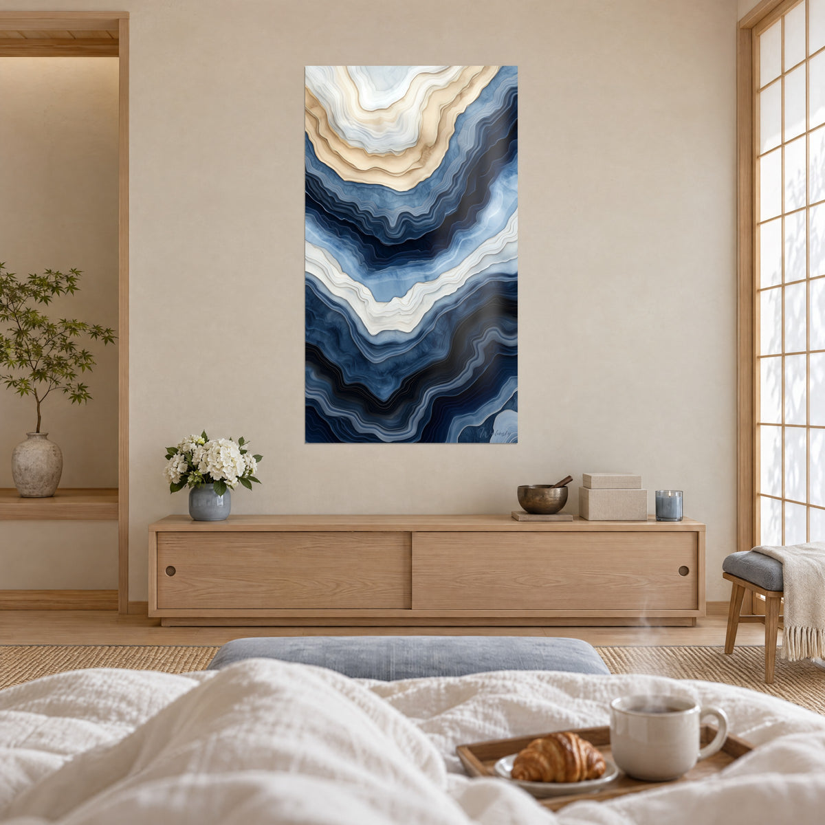 Cuadro coladas minerales en azul denim y arena dorada, de curvas fluidas, encima de una cama en un dormitorio claro