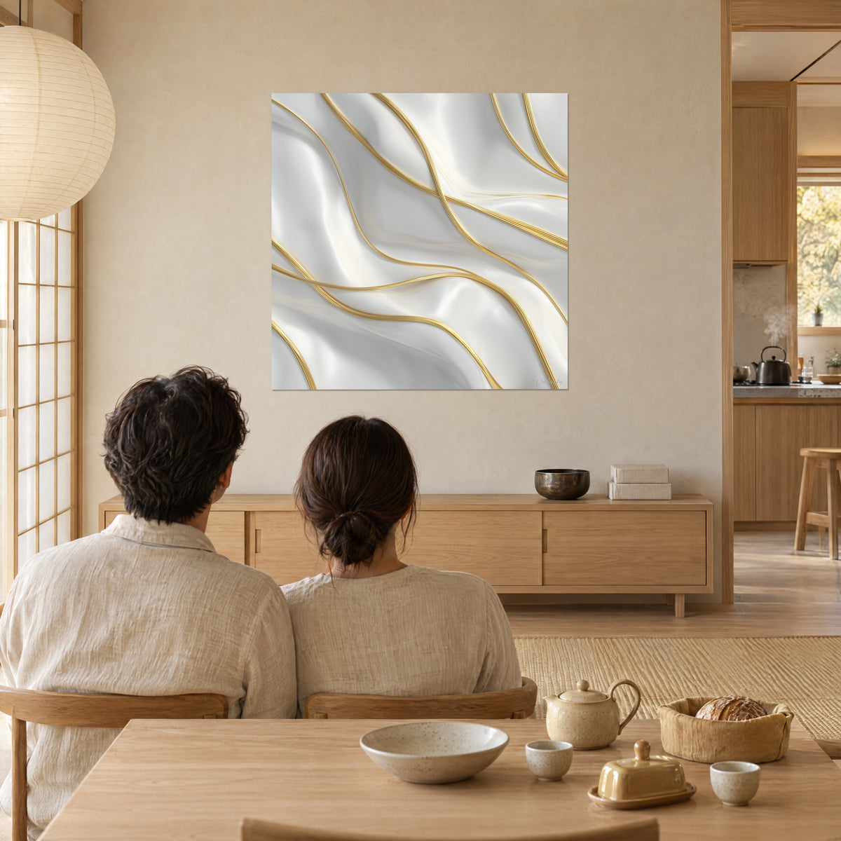 Cuadro ondas de satén perlado rayadas con líneas doradas, pareja de espaldas sentada a la mesa, pared beige y ventanal japandi