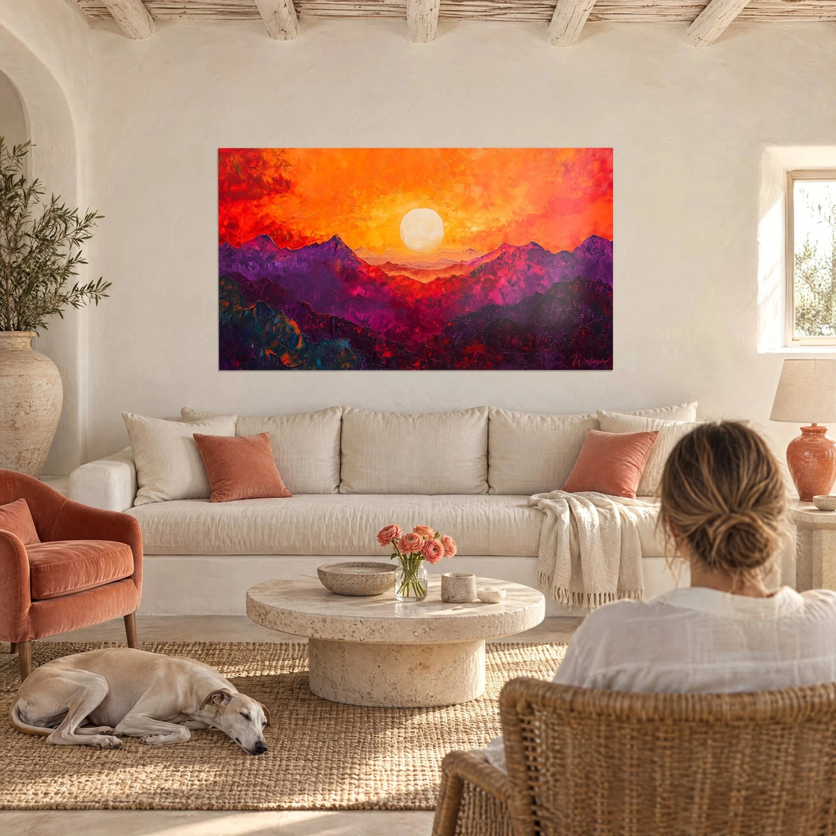 Cuadro Sol marfil sobre crestas moradas, cielo naranja y rojo, sobre un sofá en un salón luminoso
