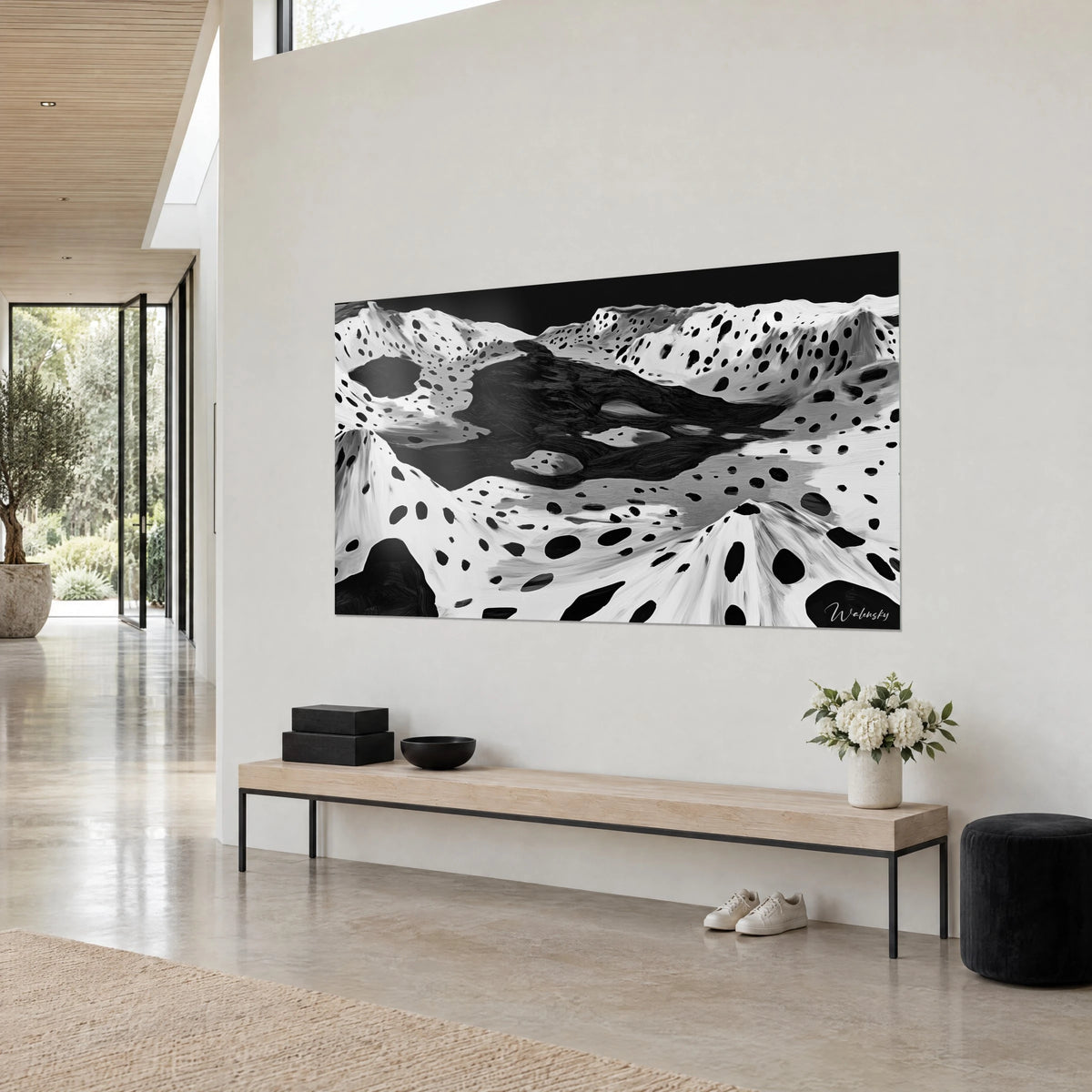 Cuadro paisaje de cráteres en blanco y negro, charcos de tinta delimitados por laderas moteadas, sobre una pared beige de un salón claro