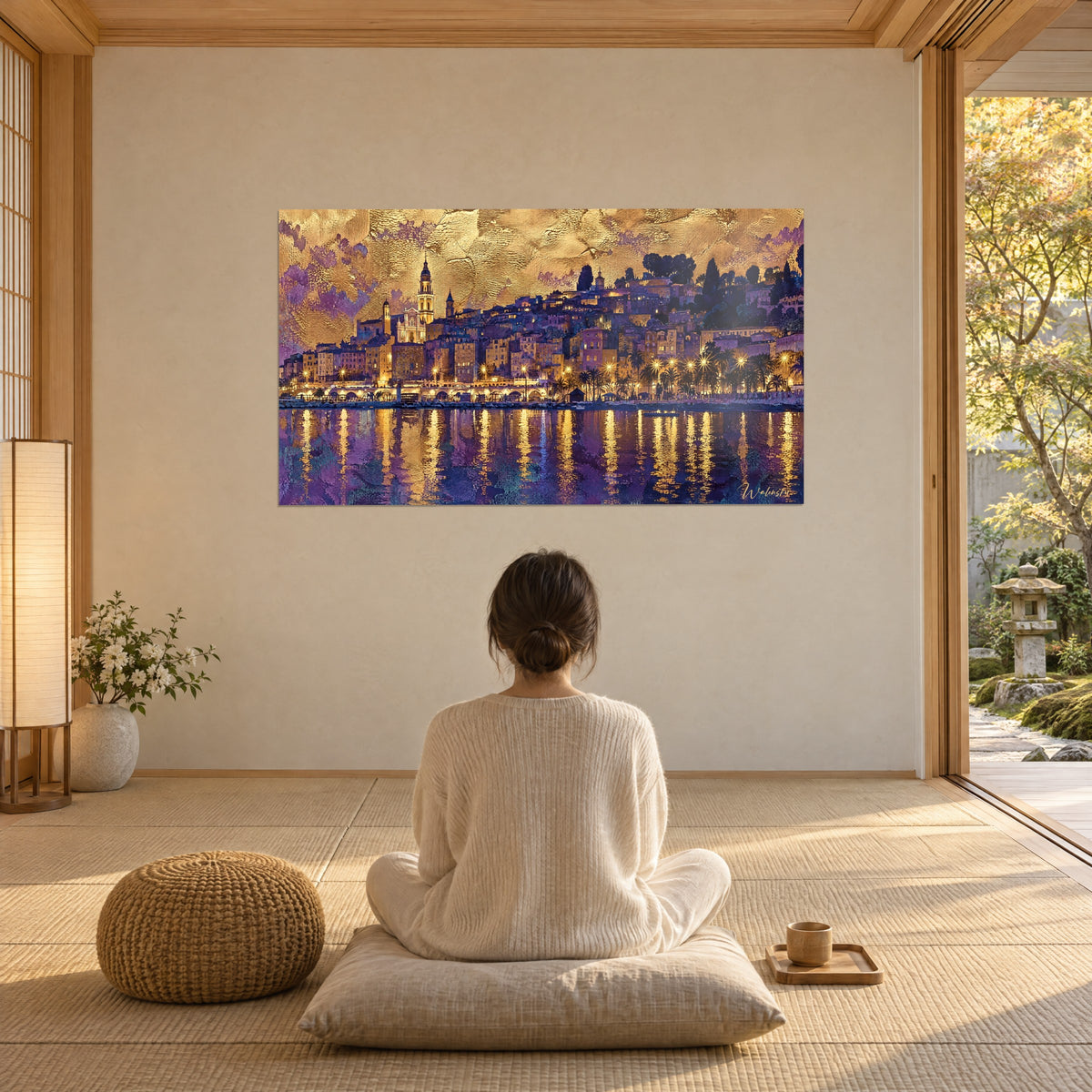 Cuadro pueblo de la Riviera con ventanas encendidas, colina de cipreses oscuros, cielo dorado y reflejos violetas, mujer de espaldas sentada sobre un cojín frente al ventanal
