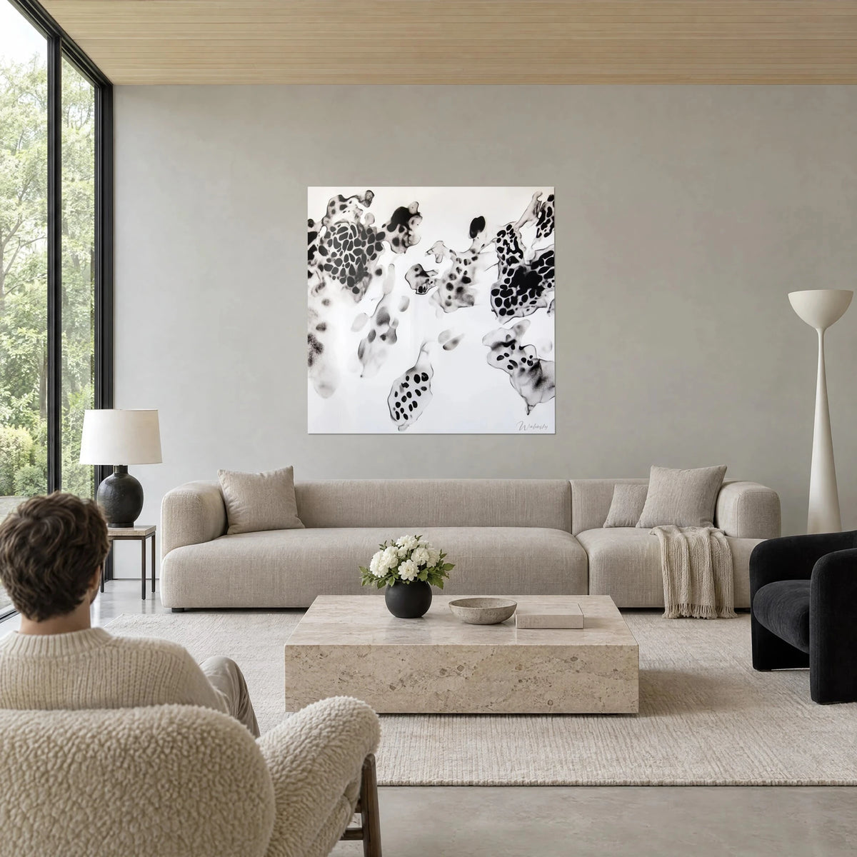 Tableau taches d'encre noires en nuée cellulaire sur fond blanc, deux personnes de dos, au-dessus d'un canapé dans un salon lumineux