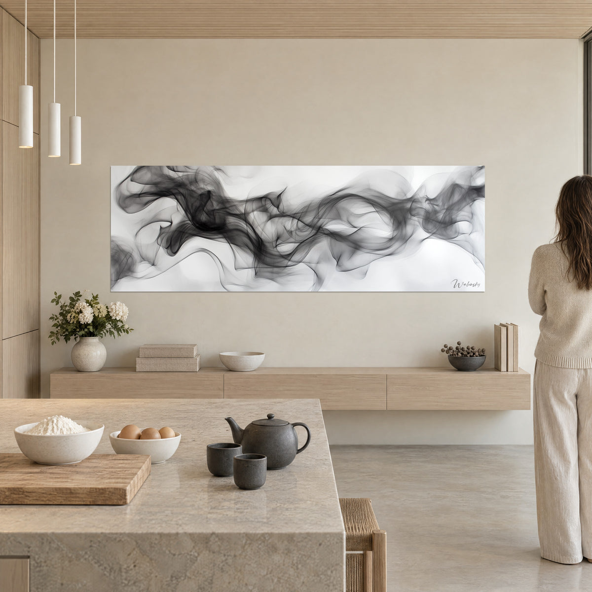 Cuadro de arabescos de vapor negro sobre blanco roto, pared beige, cocina abierta, silueta de espaldas frente a la tela
