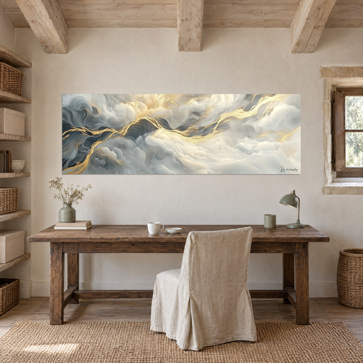 Tableau marbrures éthérées crème et dorées au-dessus d'un bureau en bois brut, chaise housse lin beige, lampe verte et mur de pierre