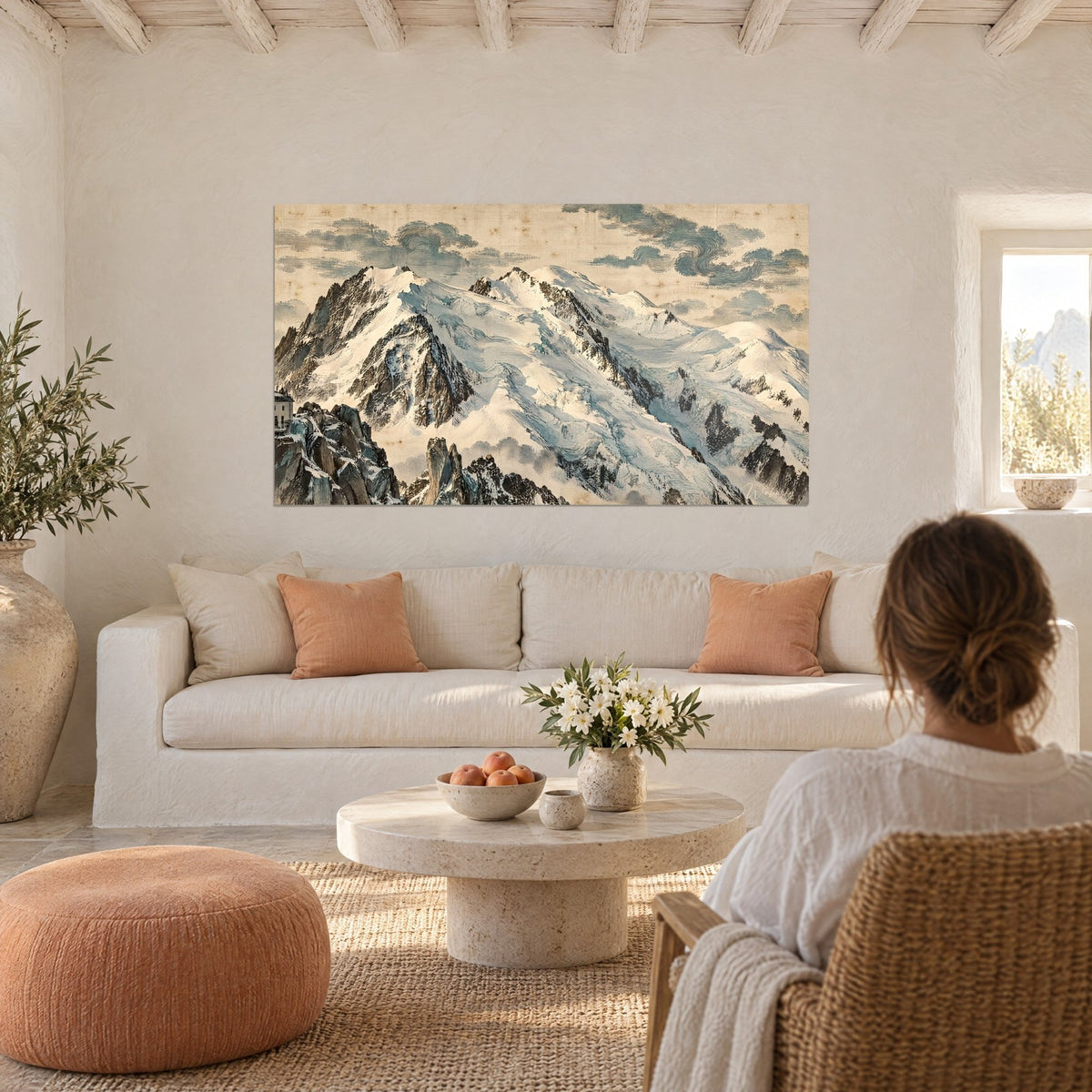 Wall art snowy Mont Blanc massif with beige and blue ridges, sculpted clouds, person seen from behind above a sofa in a bright living room