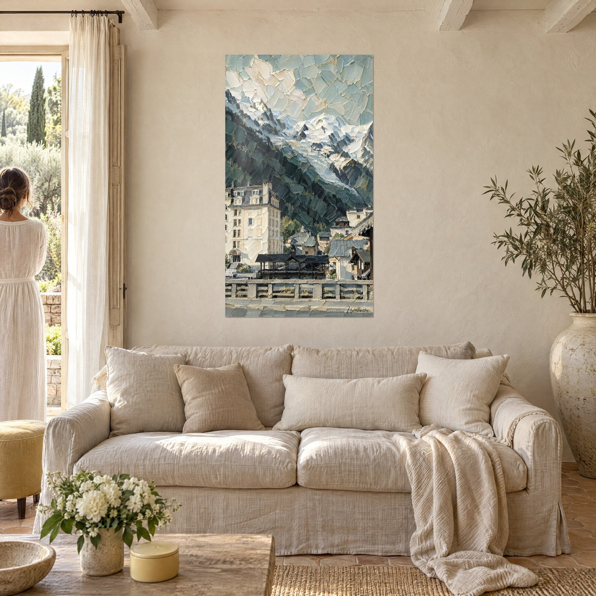 Wall art alpine village with white facades beneath a turquoise glacier and deep green fir trees, couple seen from behind, above a sofa in a bright living room