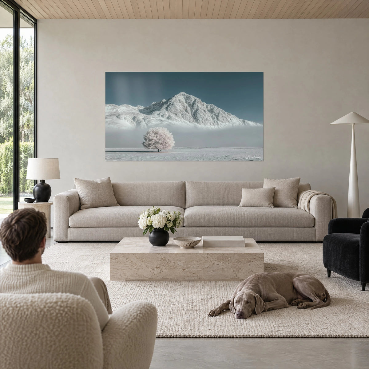 Tableau sommet enneigé dominant un arbre givré rose pâle, ciel bleu-vert, au-dessus d'un canapé dans un salon lumineux