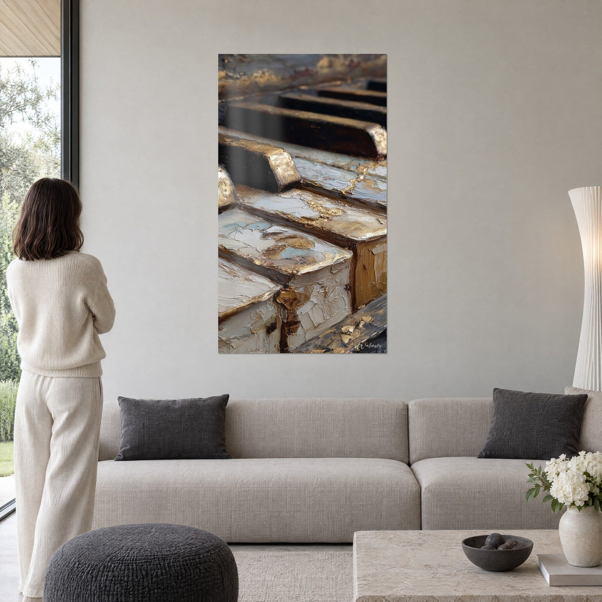 Wall art piano keys in ivory and brown with thick impasto, gold flecks, woman seen from behind, above a sofa in a bright living room