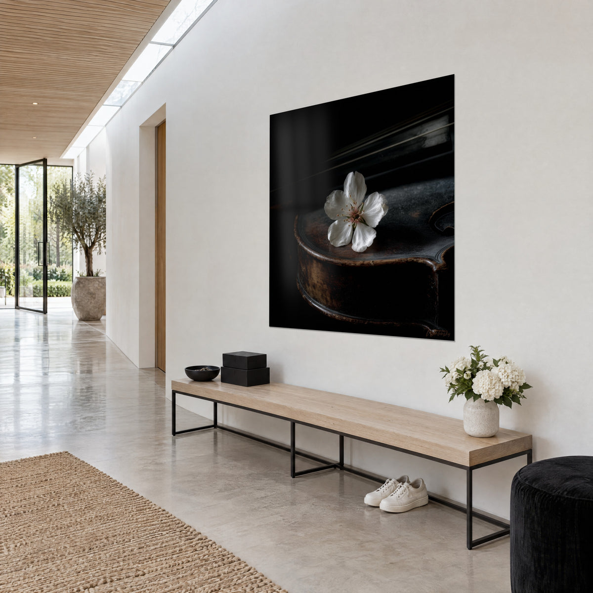 Tableau pétales ivoire et cœur rosé sur une table d'harmonie patinée, fond noir profond, mur blanc, banc en chêne clair