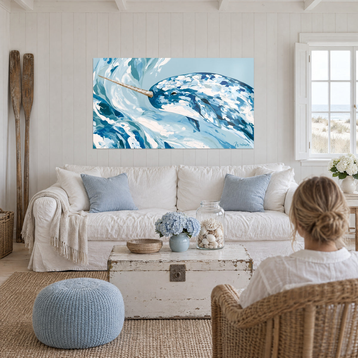 Cuadro narval con manchas azul real y blanco crema, colmillo marrón, olas de pintura gruesa, sobre un sofá en un salón luminoso