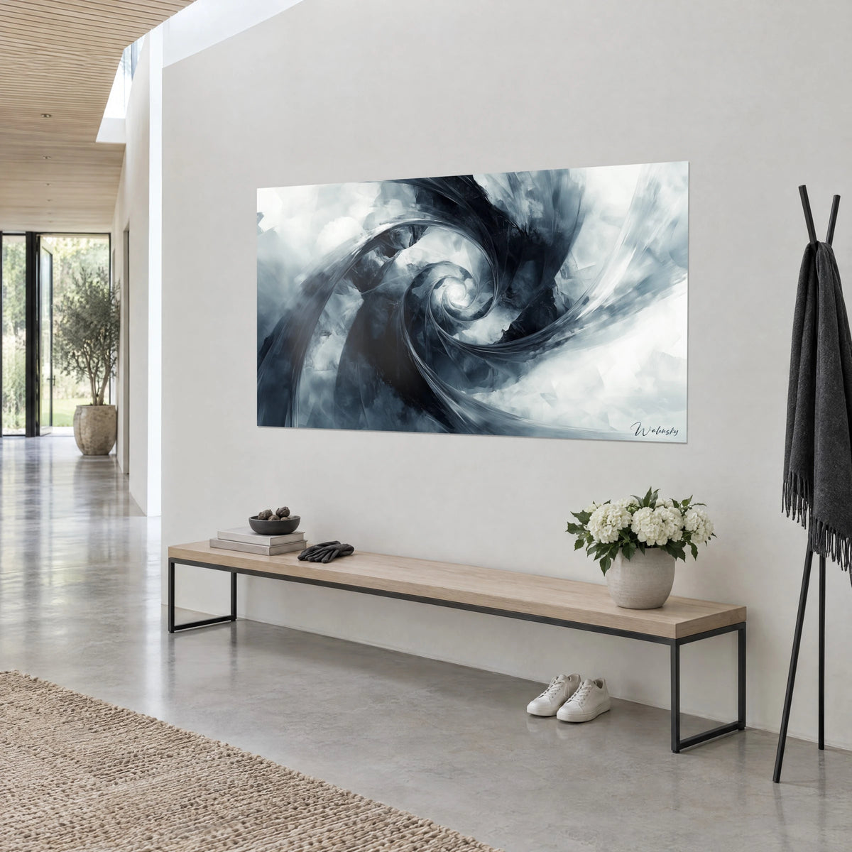 Quadro con vortice d'inchiostro nero e striature grigio acciaio con riflessi madreperlacei, su una parete bianca accanto a una panca in legno, vista di tre quarti