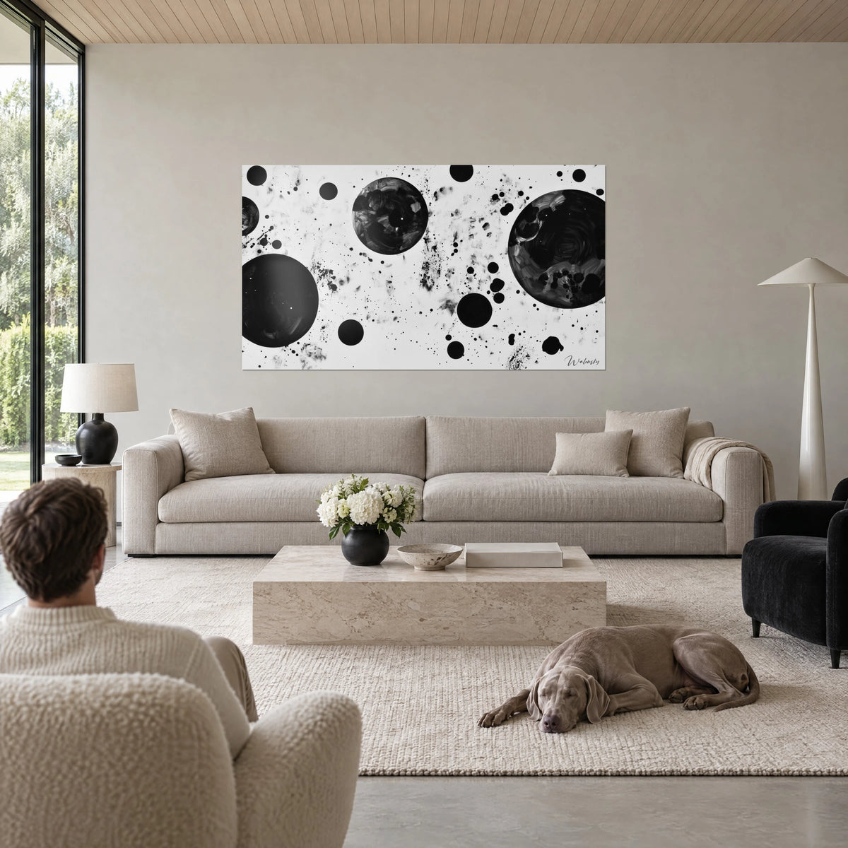 Cuadro nebulosa en blanco y negro, esferas de tinta oscura y salpicaduras grises sobre un sofá en un salón luminoso