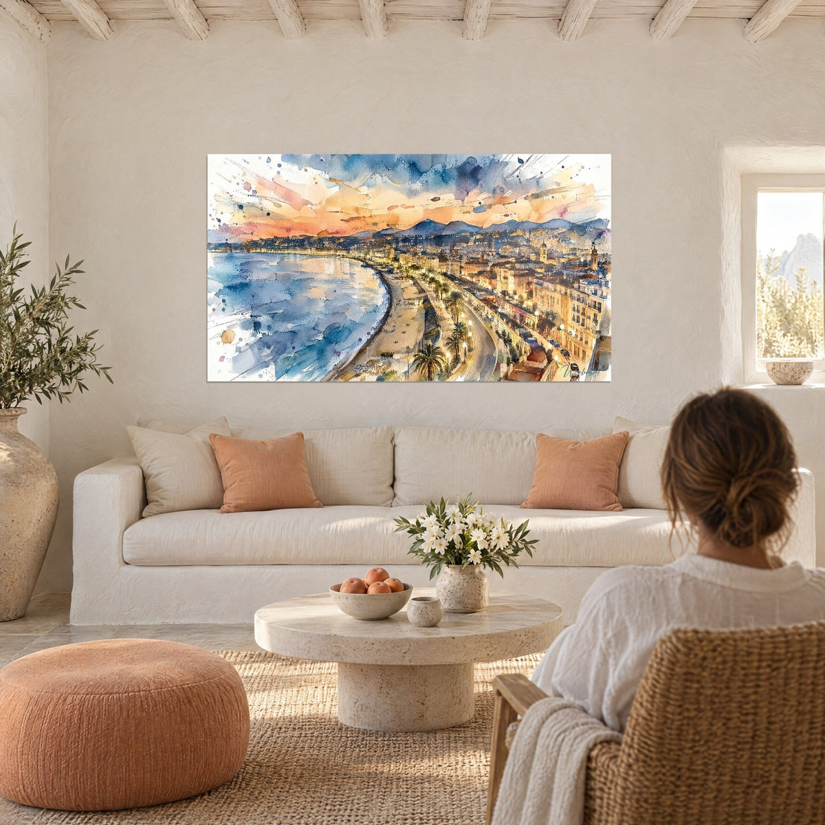 Gemälde Bucht von Nizza in Aquarell, orangefarbener und rosa Himmel über blauem Meer, mit einer Frau von hinten, über einem Sofa in einem hellen Wohnzimmer