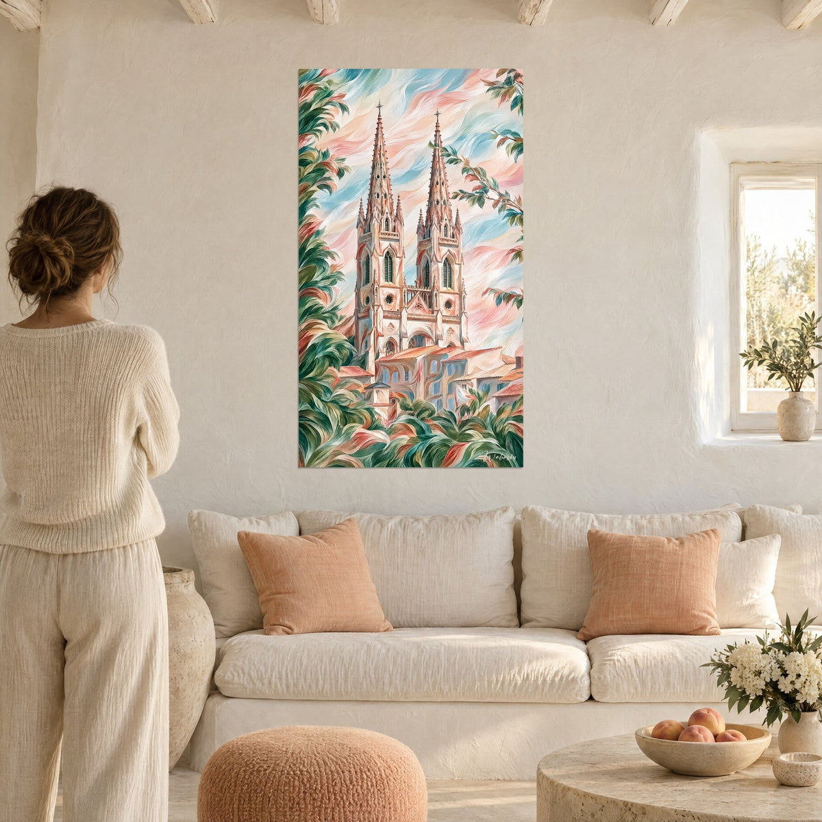 Wall art gothic cathedral with two spires in pink and turquoise, green foliage, woman seen from behind above a sofa in a bright living room