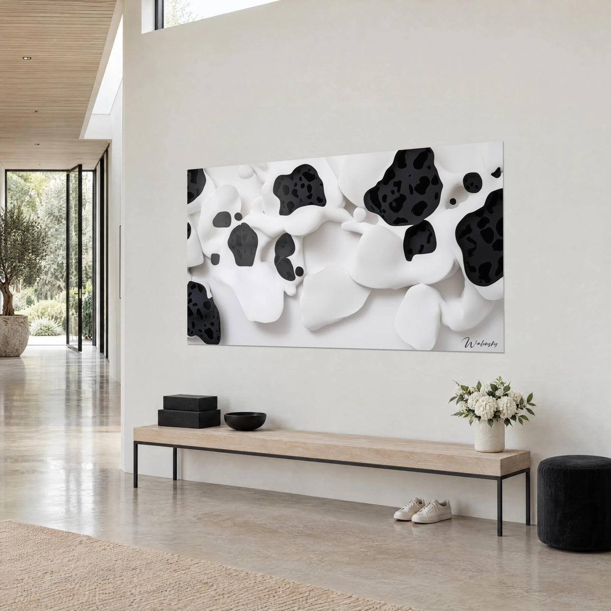 Quadro con nuvole morbide color avorio attraversate da cavità di inchiostro nero, visto di tre quarti su una parete beige accanto a una panca di legno