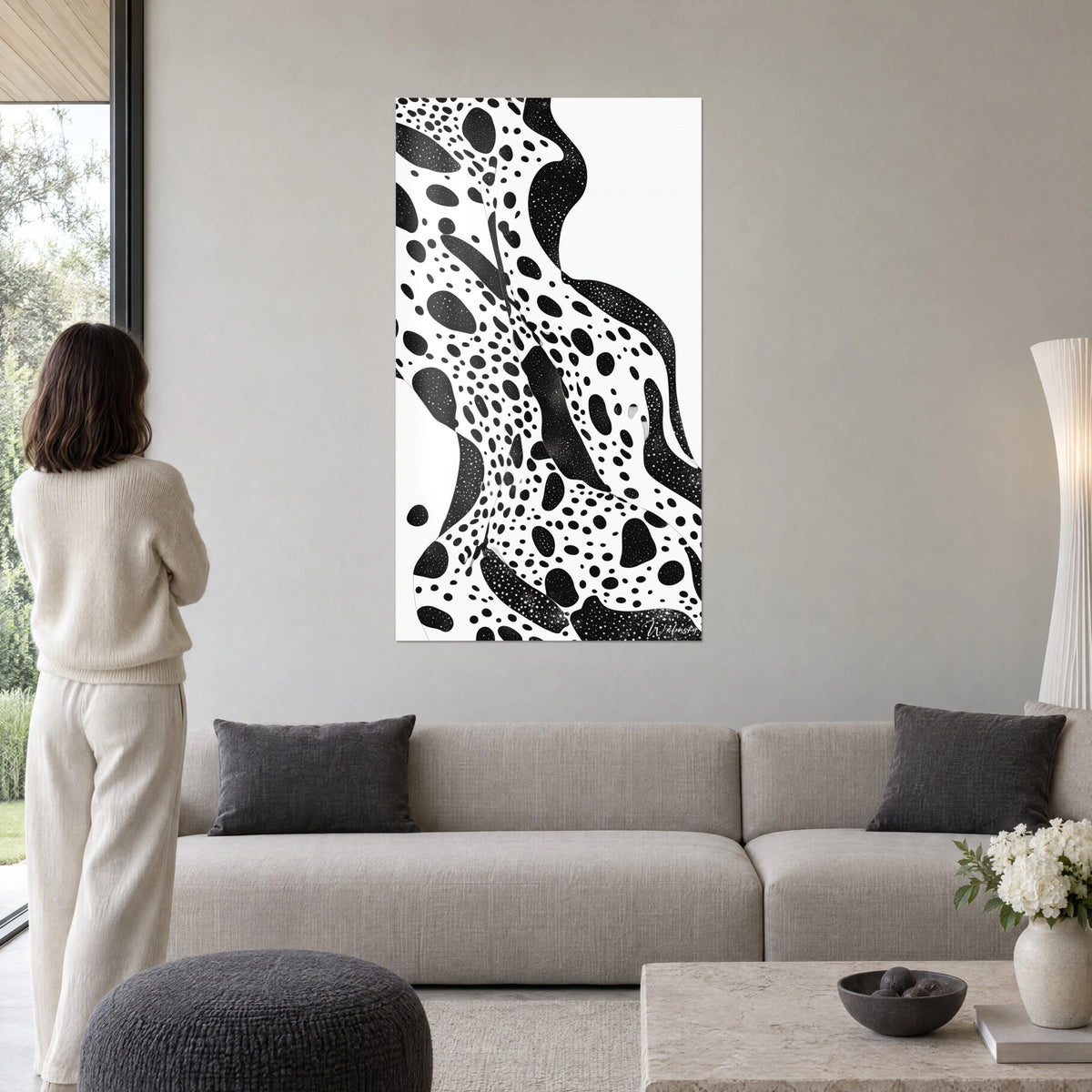 Cuadro silueta femenina moteada en blanco y negro, vista de espaldas, sobre un sofá en un salón luminoso
