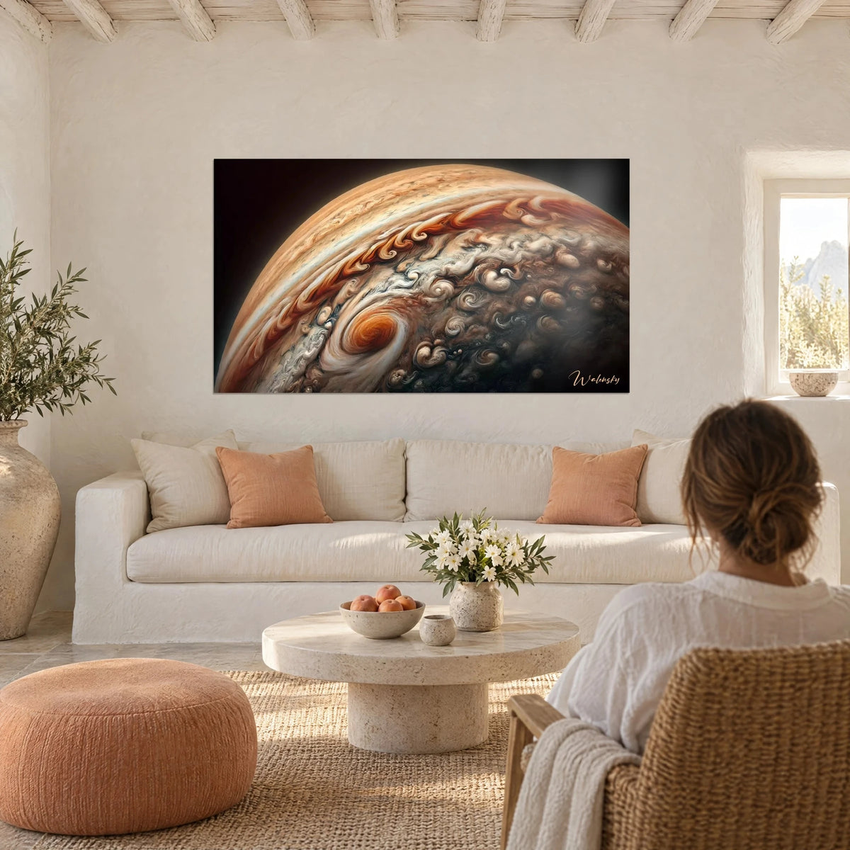 Wall art giant planet with orange and cream swirls on black background, woman seen from behind, above a sofa in a bright living room