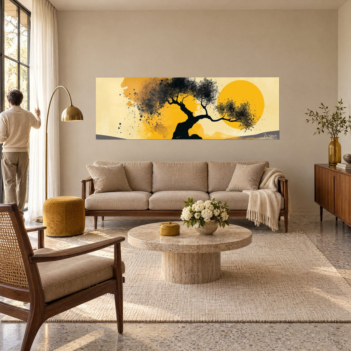 Wall art gnarled olive tree in black ink in front of a saffron-yellow disc, two people seen from behind, above a sofa in a bright living room