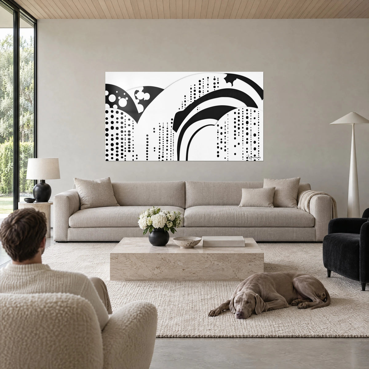 Wall art of abstract black arches on a white background, cascading dots, above a sofa in a bright living room