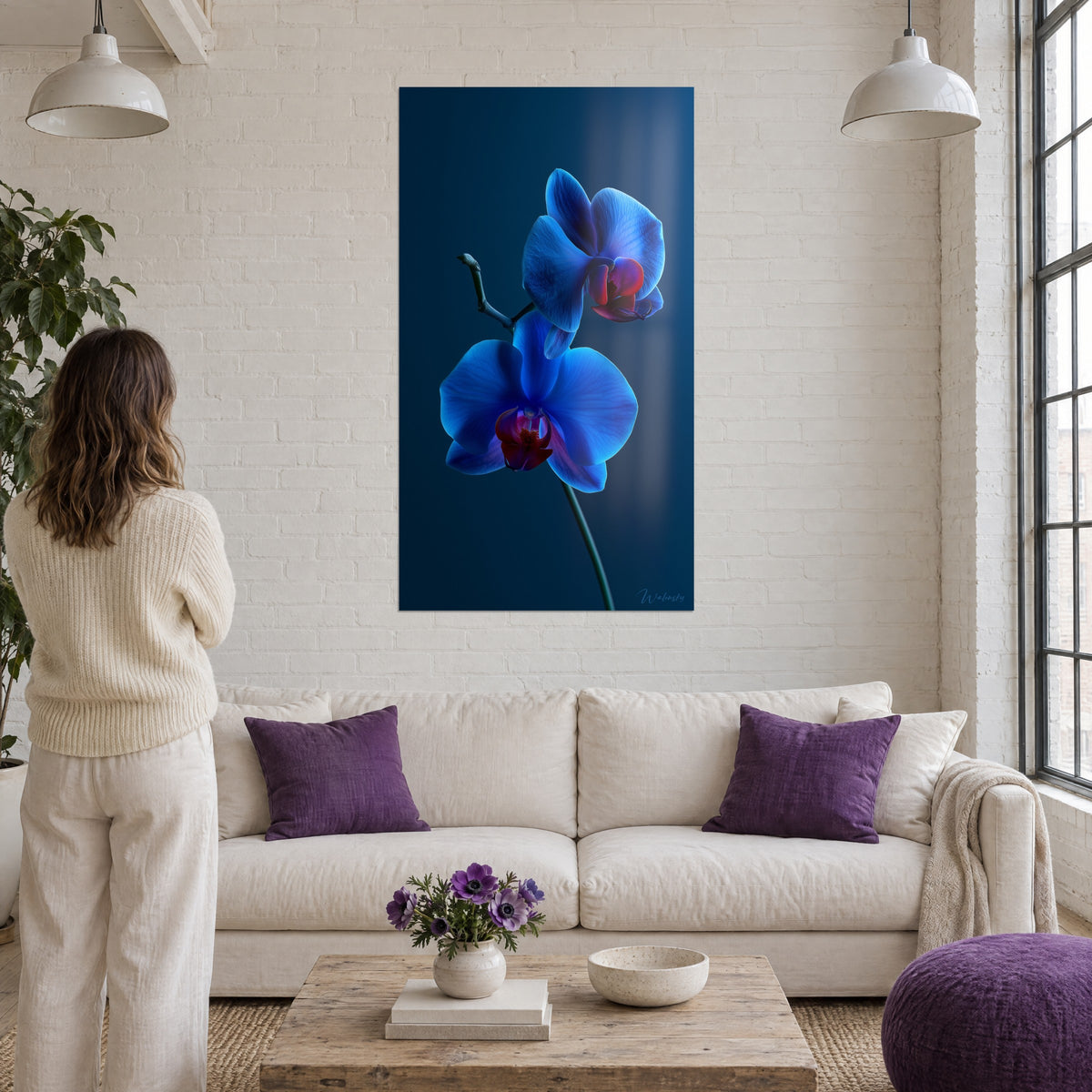 Quadro orchidea blu elettrico con cuori granata su fondo notturno, donna di spalle, sopra un divano in un soggiorno luminoso