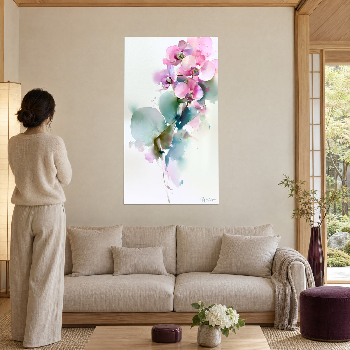 Quadro orchidee rosa ad acquerello, petali rosa pallido e foglie verde grigio, donna di spalle, sopra un divano in un soggiorno luminoso