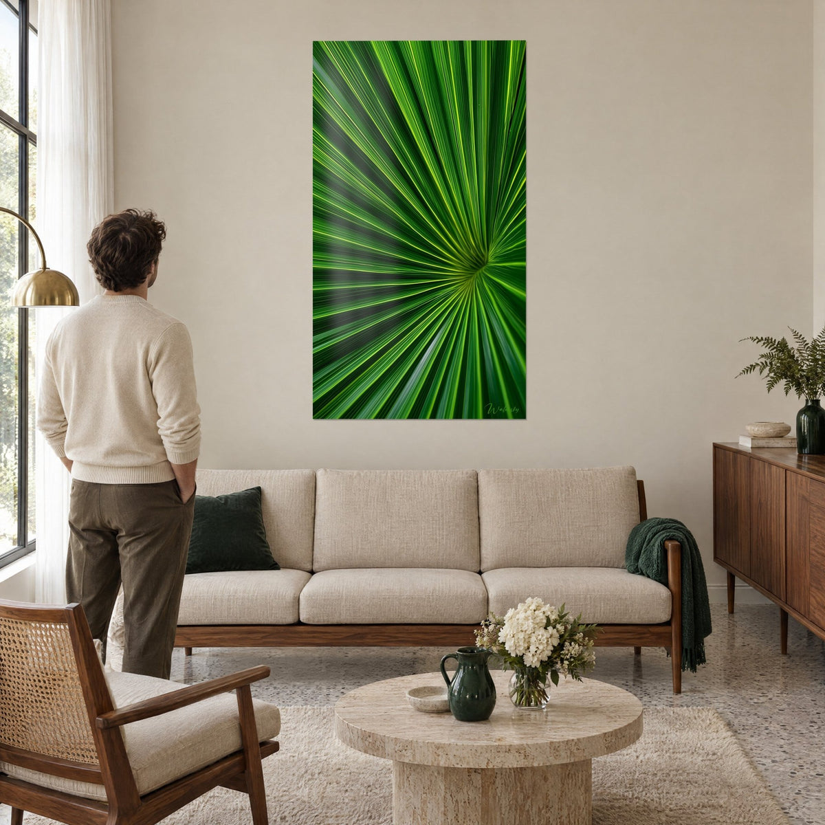 Cuadro palmera en abanico con nervaduras amarillo limón sobre verde esmeralda, un hombre de espaldas, encima de un sofá en un salón luminoso
