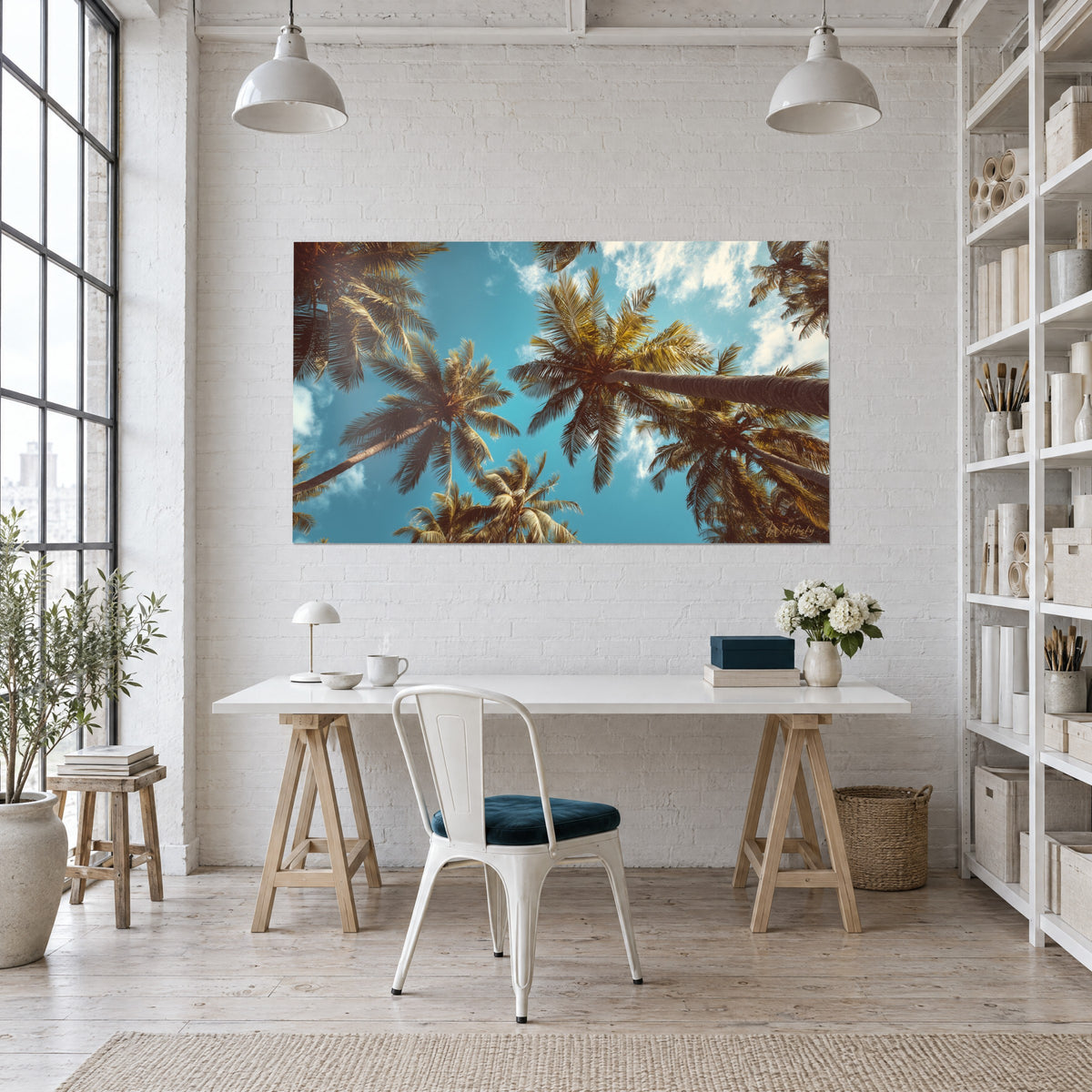 Wall art tropical palm grove in turquoise blue and copper brown, hung above a wooden desk beside white shelves