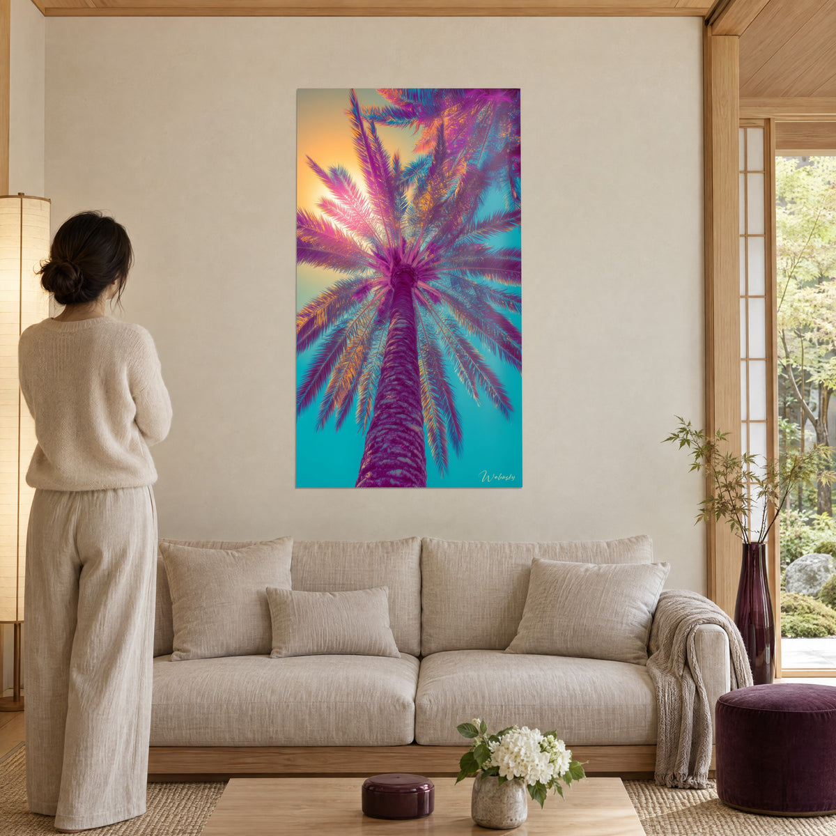 Wall art palm tree seen from below, magenta and turquoise fronds against the golden sun, above a sofa in a bright living room
