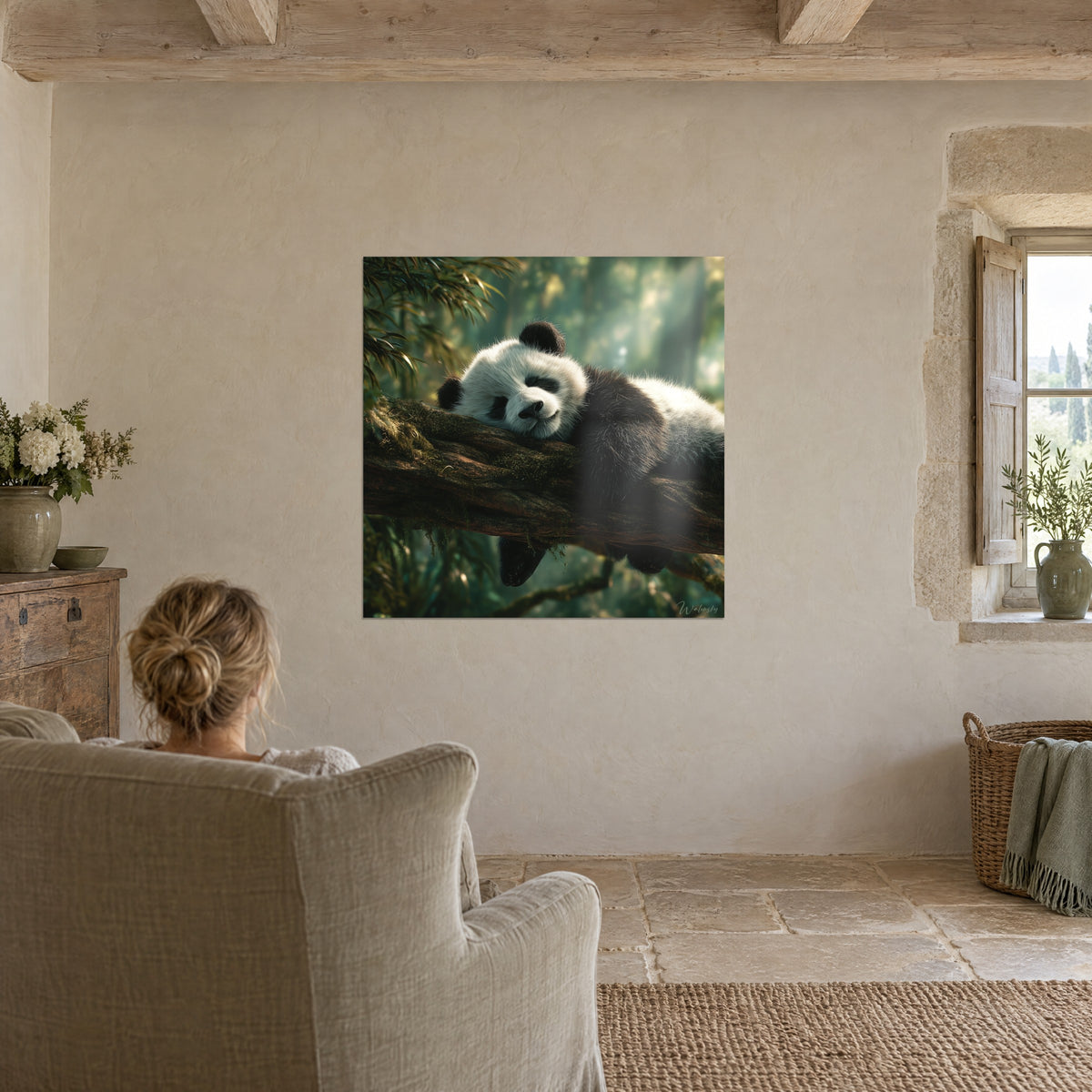 Tableau jeune panda rêveur allongé sur le tronc moussu, pelage blanc crème et noir, accroché face à une femme de dos dans un fauteuil gris-vert
