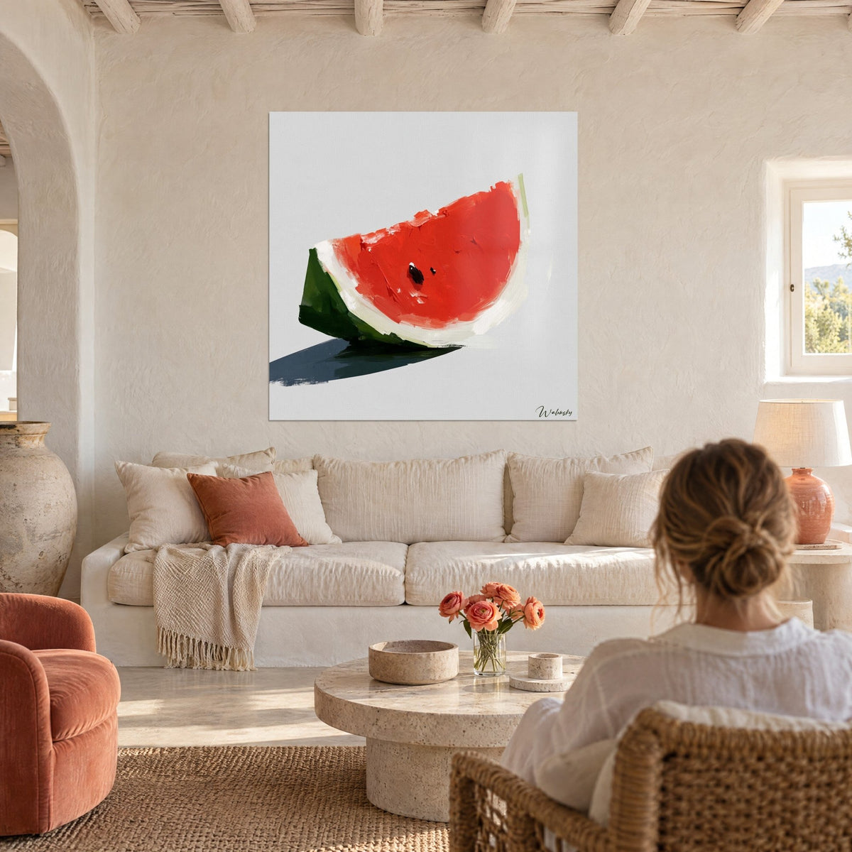 Wall art watermelon wedge in vermilion red and fir green with a blue-tinged shadow, above a sofa in a bright living room