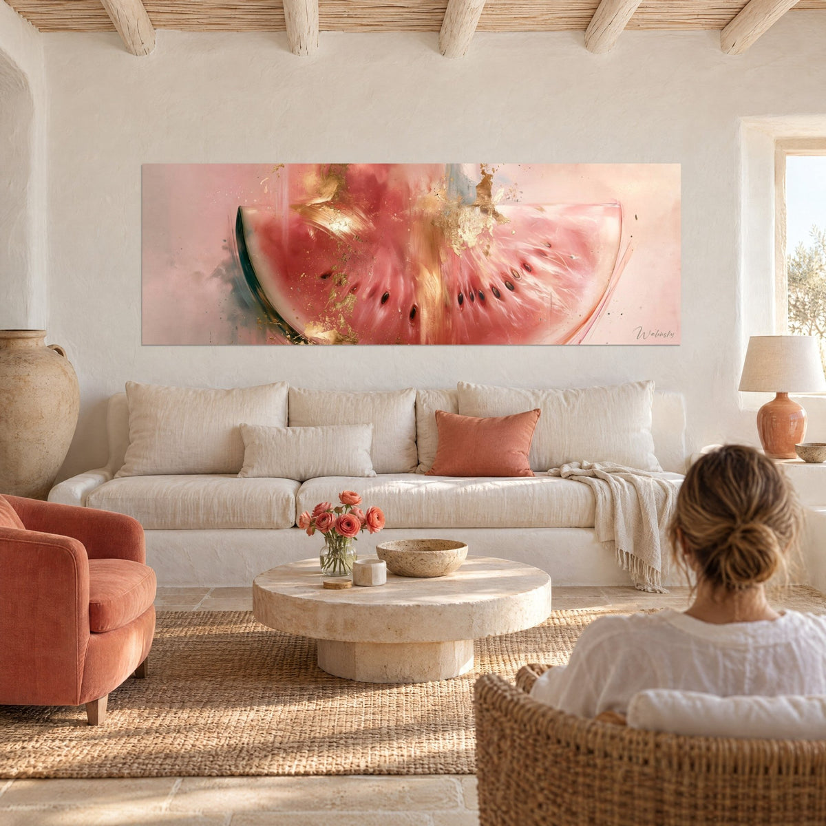 Wall art pink watermelon half splashed with gold, black seeds in an arc, woman seen from behind above a sofa in a bright living room
