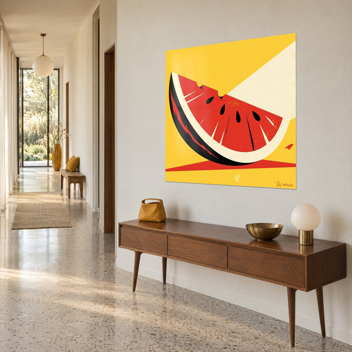 Wall art watermelon wedge in flat red and cream tones, black seeds on a yellow background, three-quarter view in a hallway