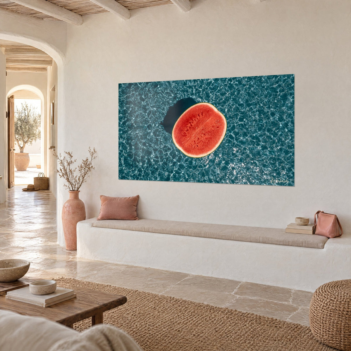 Wall art summer fruit cut in half, vivid red flesh and cream rind on sparkling turquoise water, three-quarter view, white banquette