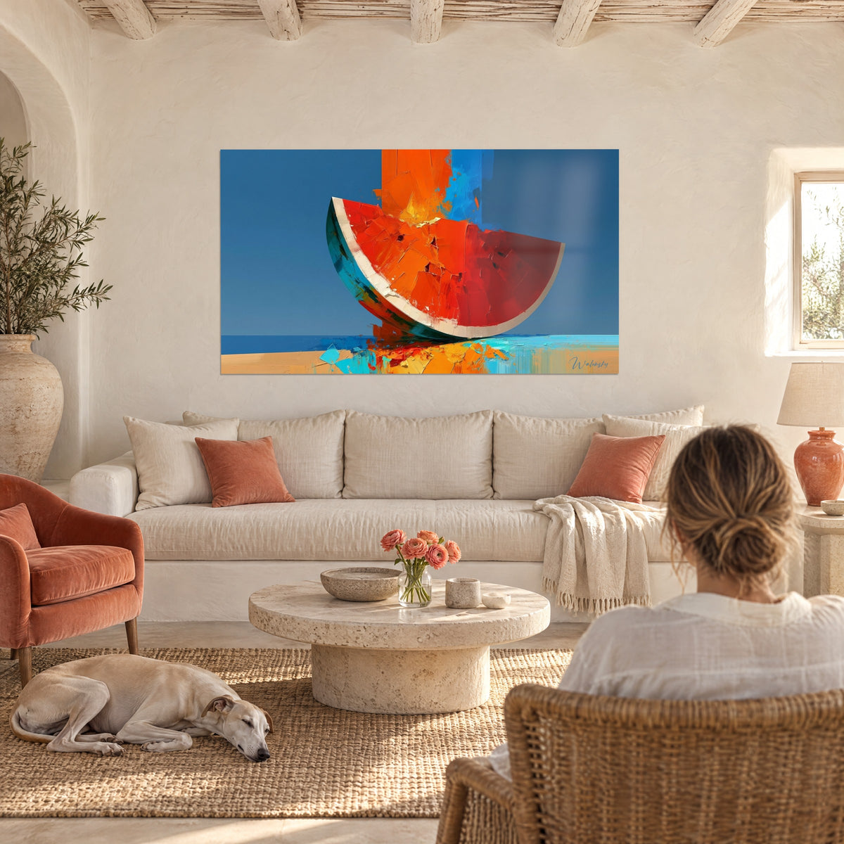 Wall art watermelon quarter in vermilion red against a midnight blue sky, two people seen from behind, above a sofa in a bright living room