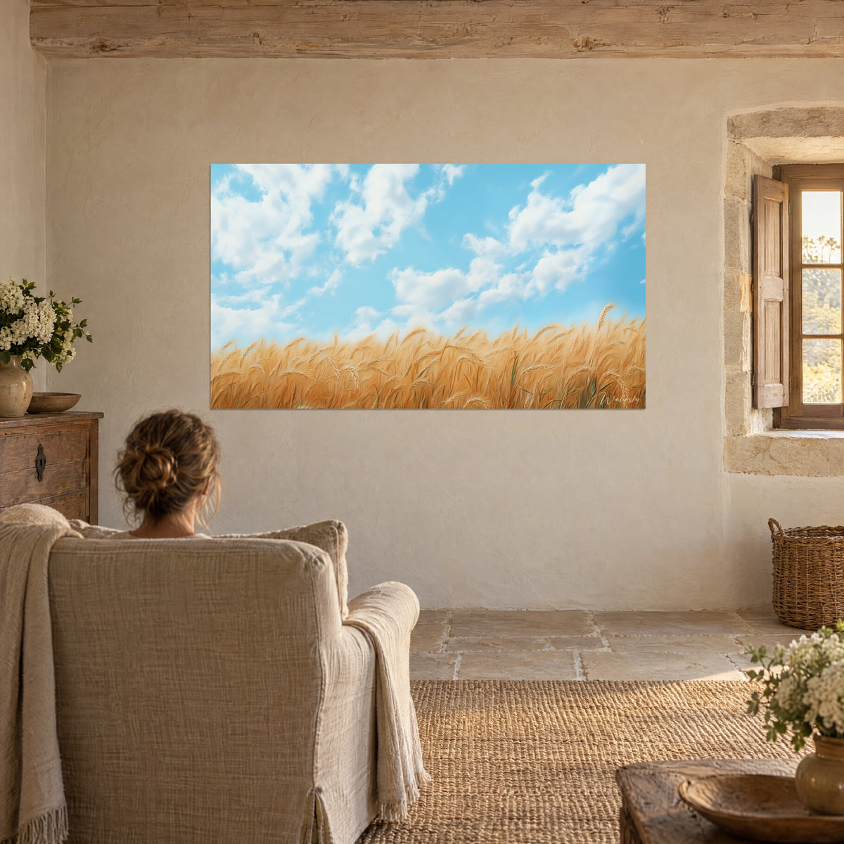 Cuadro de campos de trigo resplandecientes bajo una bóveda azul salpicada de nubes blancas, vista desde un sillón de lino junto a una ventana