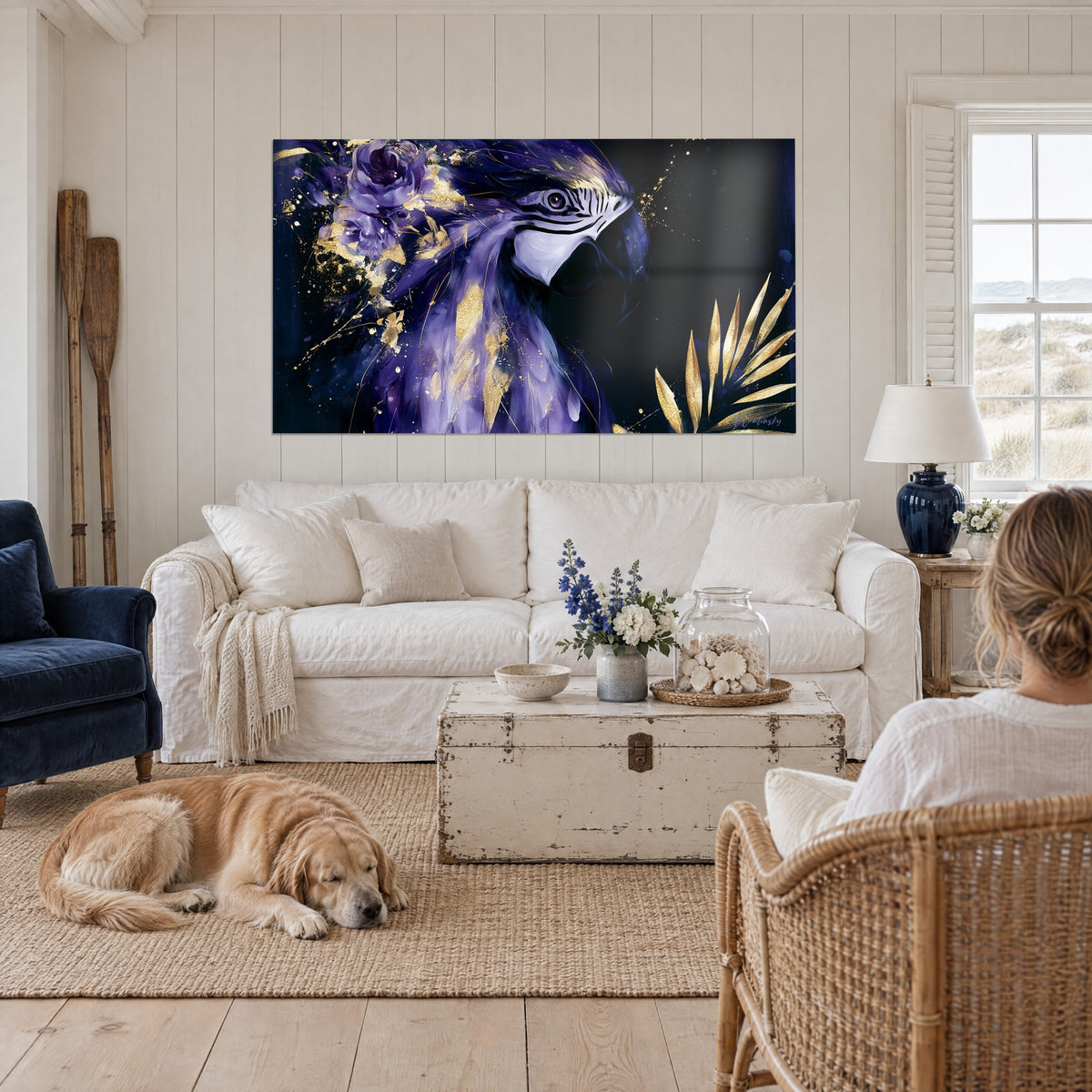 Tableau ara de profil, plumes violettes et éclats dorés, fleur mauve, au-dessus d'un canapé dans un salon lumineux