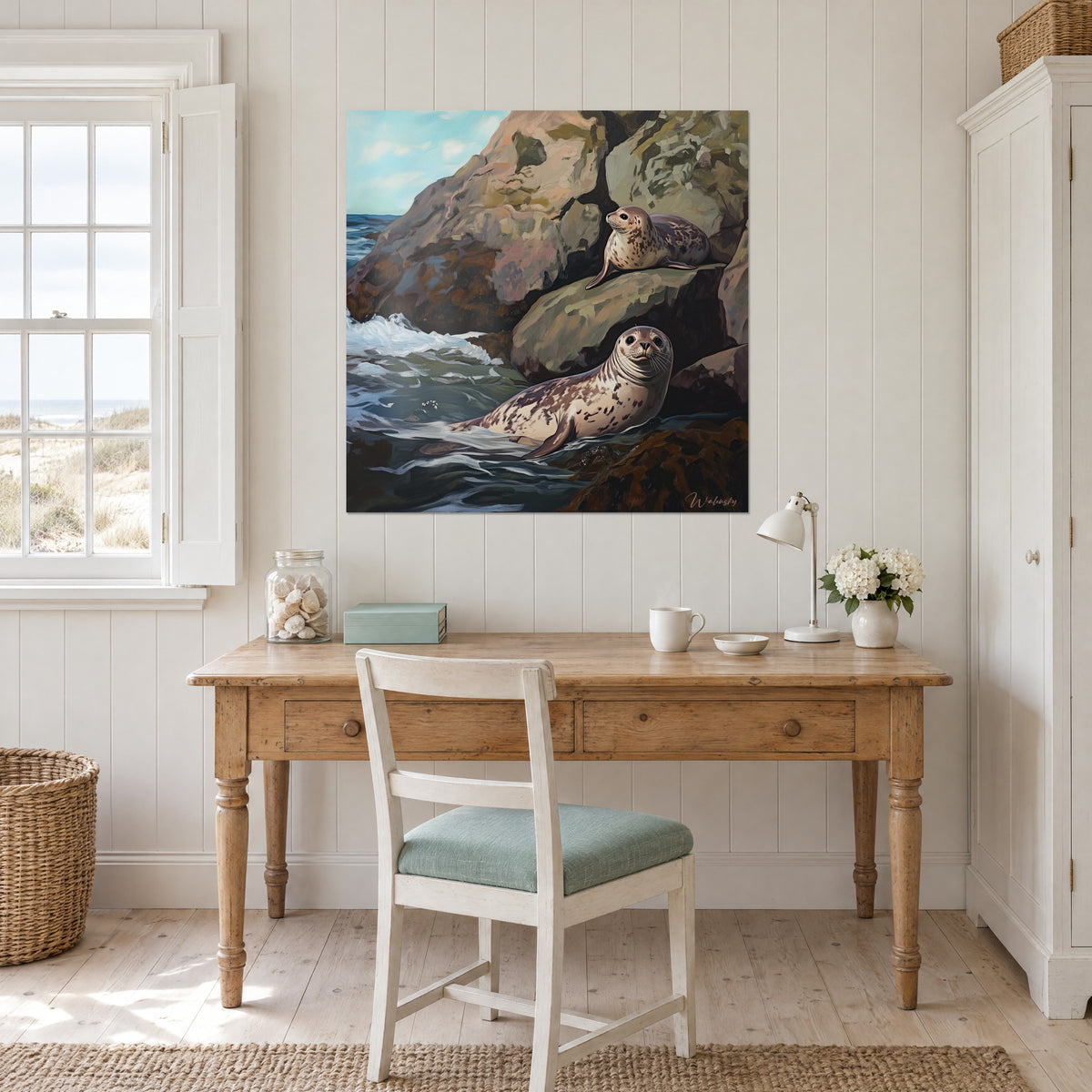 Schilderij grijze gevlekte zeehond die het hoofd opheft, beige-roze klif, bleek turquoise lucht, boven een bureau van licht hout