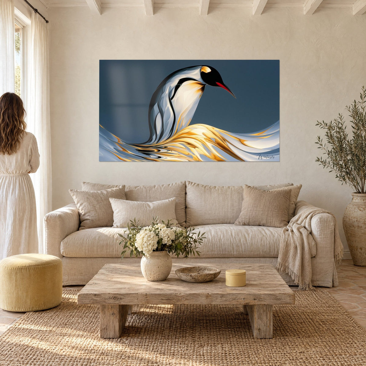 Tableau manchot au dos noir et bec rouge, vagues dorées sur fond bleu nuit, femme de dos, au-dessus d'un canapé dans un salon lumineux