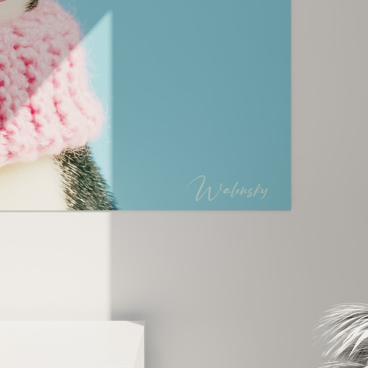 Grain du tricot rose et vert menthe visible en détail sur cette œuvre accrochée représentant un pingouin
