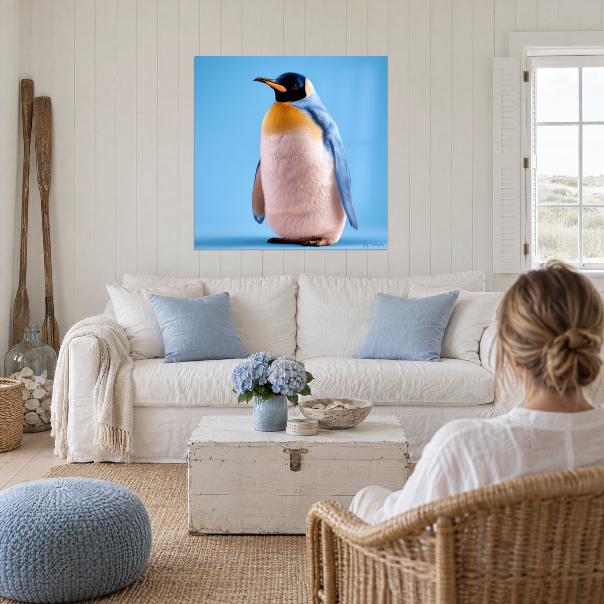 Tableau manchot au plastron doré et ailes bleu ciel, ventre blanc duveteux, au-dessus d'un canapé dans un salon lumineux