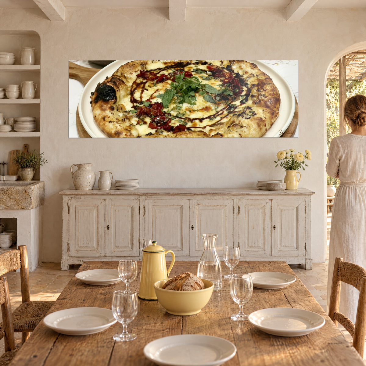 Obraz roztopiona mozzarella i ciemne nitki balsamico na kremowej i czerwonej pizzy, kobieta w jasnej sukience tyłem przy stole
