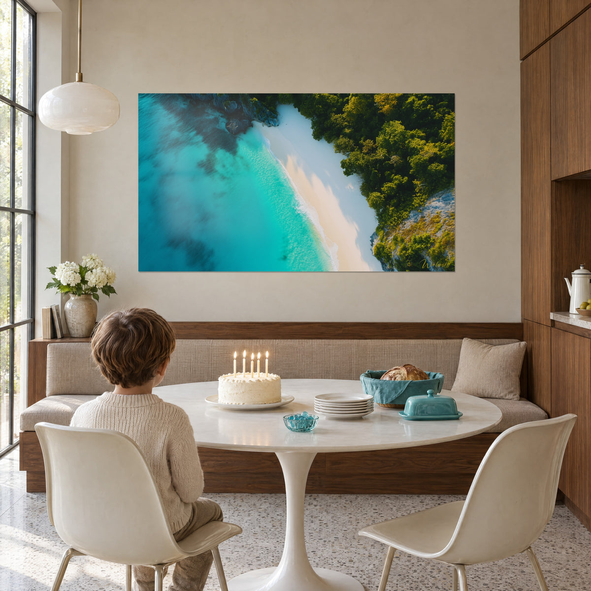 Tableau baie paradisiaque vue de drone, mer bleu-vert et lisière de forêt dorée, face à une table ronde blanche et un gâteau
