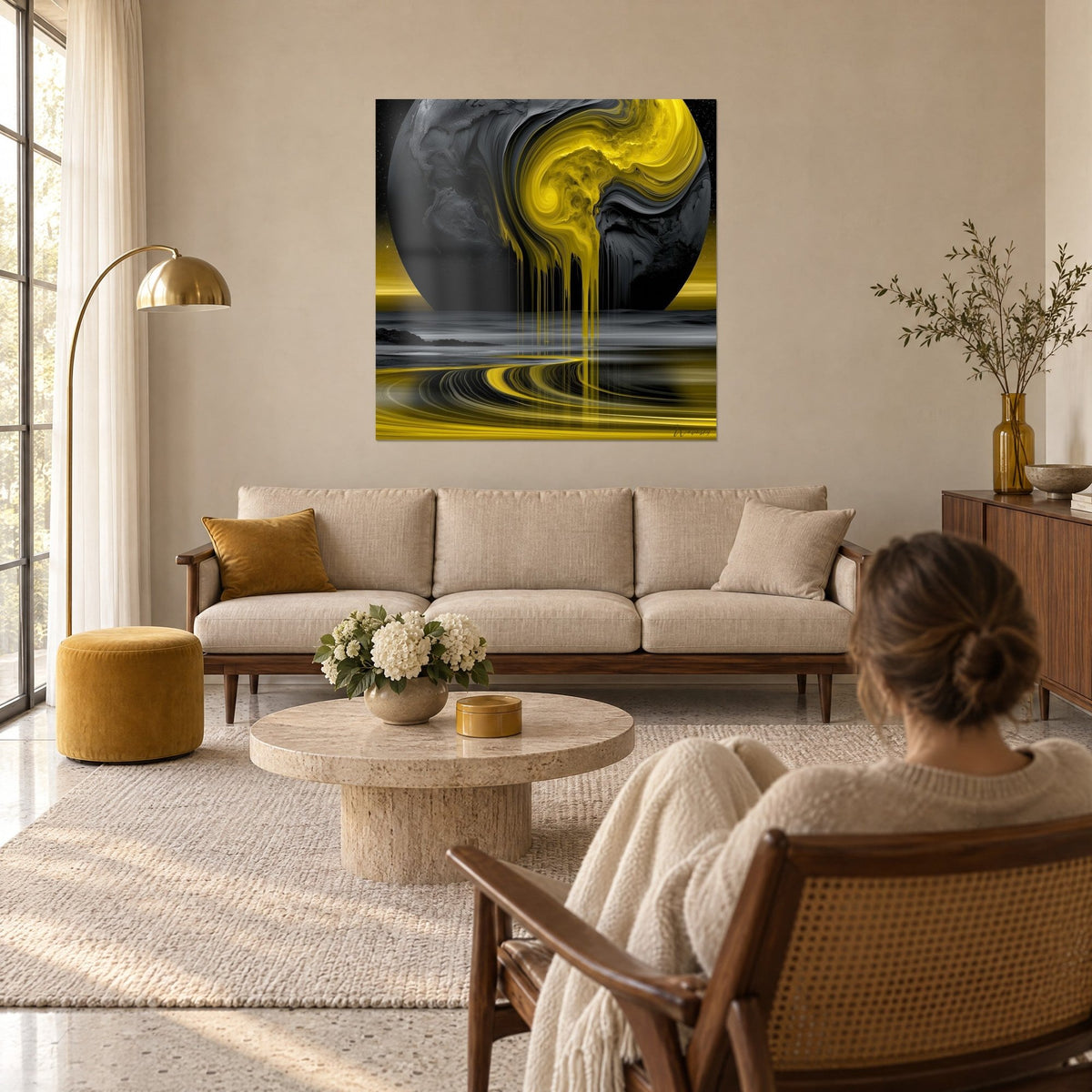 Tableau globe noir charbon aux coulées jaune citron, accroché devant une femme de dos, au-dessus d'un canapé dans un salon lumineux