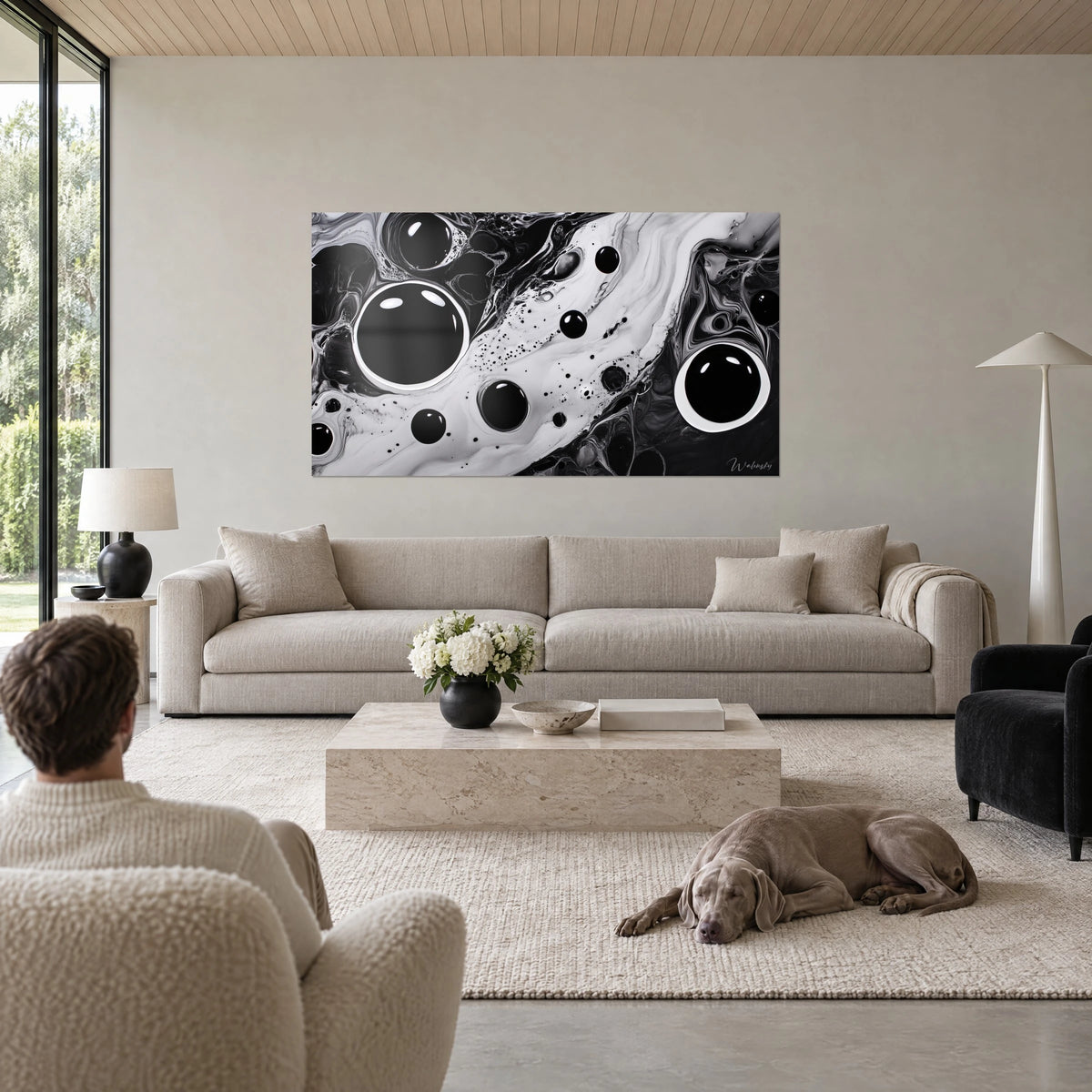 Gemälde mit schwarzen Tintenblasen auf weißem Marmoreffekt, zwei große, hell umrandete Scheiben, Mann von hinten und Weimaraner über einem Sofa in einem lichtdurchfluteten Wohnzimmer