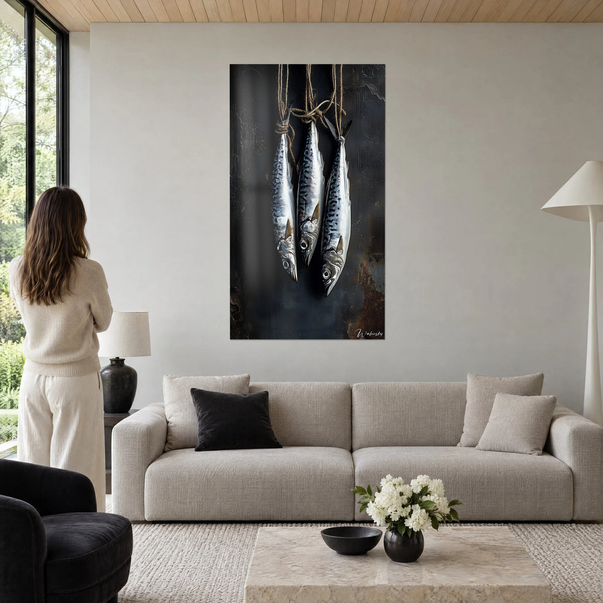 Cuadro con tres caballas plateadas colgadas de un cordel, fondo negro carbón, óxido marrón, encima de un sofá en un salón luminoso
