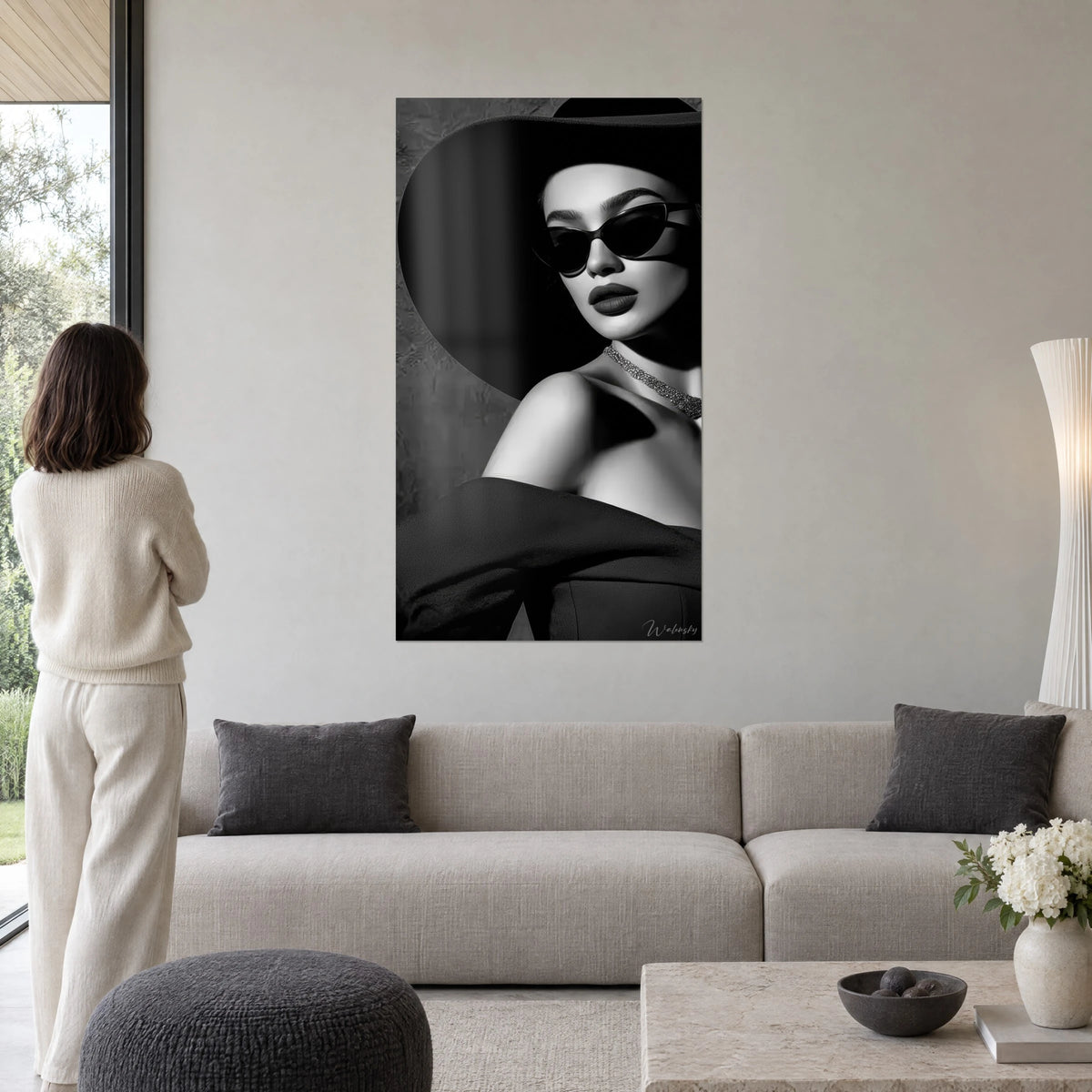 Schilderij chic portret van een vrouw met zwarte hoed met brede rand, vlinderbril en glinsterende ketting, zwart-wit, boven een bank in een lichte woonkamer