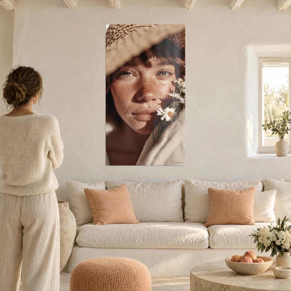 Schilderij gezicht vol sproeten onder een strohoed, witte madeliefjes en crèmekleurige trui, boven een bank in een lichte woonkamer