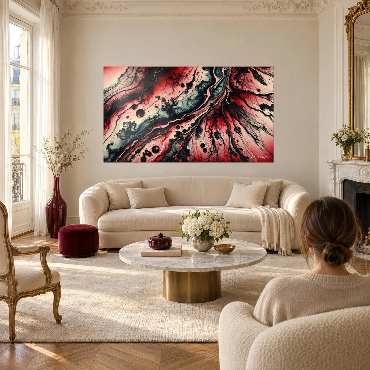 Wall art with fluid pours in carmine red and jet black, branching grey veins, seen from behind by a woman above a sofa in a bright living room