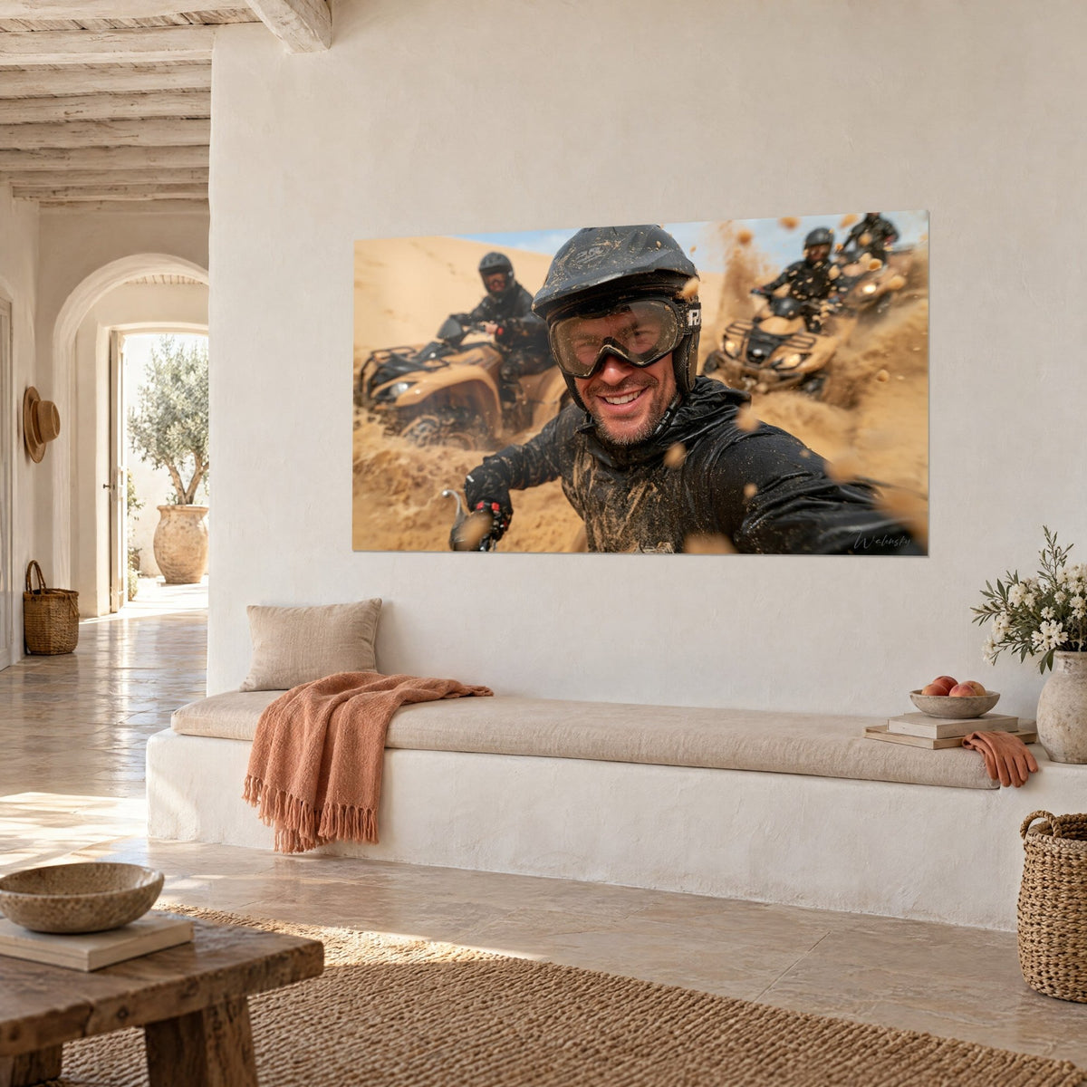 Quadro di un selfie di un motociclista barbuto con occhiali infangati, quad beige sabbia sullo sfondo, parete bianca di una casa mediterranea
