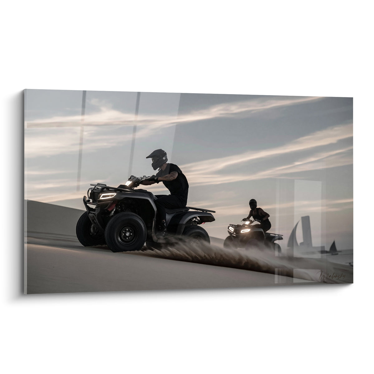 Quad noir mat filant sur une dune beige sous un ciel gris-orangé strié de nuages